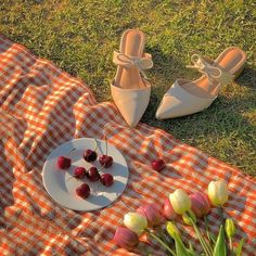 a plate with cherries on it next to a pair of white shoes and tulips