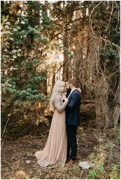 a man and woman standing next to each other in the woods