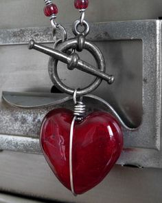 Ver. 9 // NEW: Larger heart pendant! Heart of darkness. Perfect gift for the not-so-girly-girl. Forget the sticky-sweet heart... this has edge. A gloriously-glossy glass heart pendant in sultry, regal red has been wrapped and bound in oxidized sterling silver wire and suspended from a gunmetal black toggle clasp and chunky antiqued silver plated chain. Please note that each heart is slightly different, but each one is gorgeous! NEW: Larger heart pendant! Deep red glass heart pendant: approx. 1" Valentine's Day Silver Glass Necklaces, Valentine's Day Silver Glass Necklace, Glass Jewelry With Heart Charm For Valentine's Day, Heart-shaped Glass Necklace For Valentine's Day, Heart-shaped Glass Jewelry For Valentine's Day, Valentine's Day Jewelry With Heart Charm And Glass Material, Valentine's Day Glass Jewelry With Heart Charm, Valentine's Day Heart-shaped Wire Wrapped Necklace, Valentine's Day Heart-shaped Glass Necklace