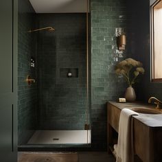 a bathroom with green tiles and a gold faucet next to the bathtub