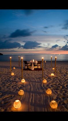 a table set up on the beach with candles