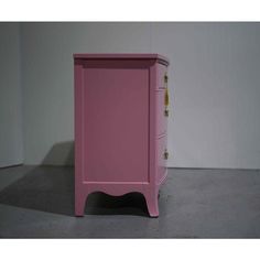 a pink nightstand with two drawers on the bottom and one drawer open, in front of a white wall