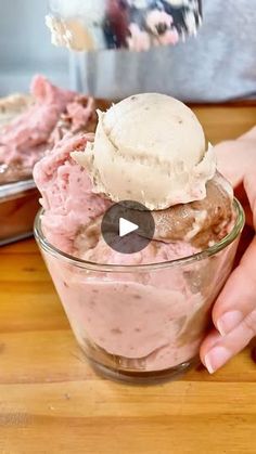 a person holding a bowl of food with ice cream in it on top of a wooden table