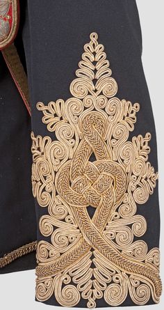 the back side of a black jacket with gold embroidery on it and an intricate design