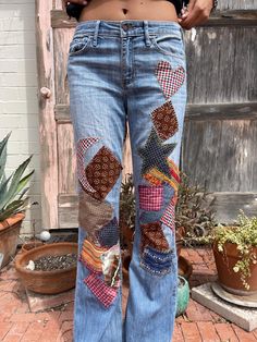 a woman wearing jeans with patches and hearts on the side, standing in front of a door