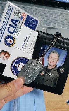 a person holding up a id card with a laptop in the background