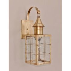 an old fashioned brass wall light on a white wall with a glass block in the middle