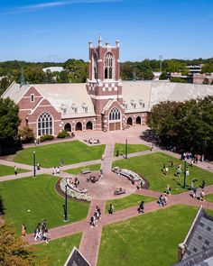 an aerial view of a campus with people walking around and sitting on the grass in front of it