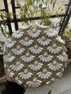 This is a beautiful handcrafted clutch bag made with love.It has intricate handwork which showcases the Indian craftsmanship by our local artisans. It comes with a metal sling chain. Details  - Single side handwork  - Fabric lining on the inside to keep your belongings safe  - Metal lock closure  - Ring knob - Detachable sling chain  This clutch can be worn as a crossbody bag or a shoulder bag with the sling chain or can simply be carried in hand.It is spacious enough to carry mobile phones, lipsticks, Keys and other small accessories. Dimension  Standard size - 7x7 inches  Please Note - Every clutch is handmade so slight pattern variation might be there. - There can also be slight colour variation due to natural light set up. Luxury Handwork Wedding Set, Indian Wedding Gifts, Indian Gifts, Embroidered Clutch, Handmade Clutch, Designer Clutch, Luxury Bag, Bride Gift, Local Artisans