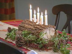 a table topped with a cake covered in pine cones and candles next to a chair