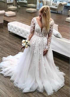 a woman in a white wedding dress standing on a wooden floor next to a couch