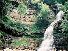 there is a waterfall in the middle of some rocks and trees on the other side