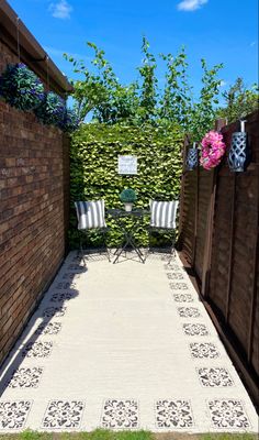 an outdoor patio area with chairs, table and potted plants on the side wall