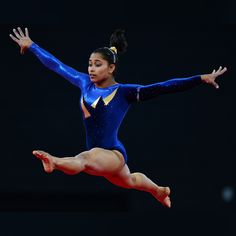 a young woman is performing on the balance beam with her arms outstretched and legs spread out