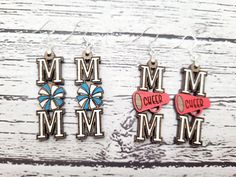 three earrings with the words mm and m on them, sitting next to each other