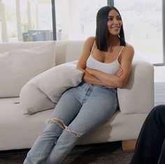 a woman sitting on top of a white couch next to a man in black pants