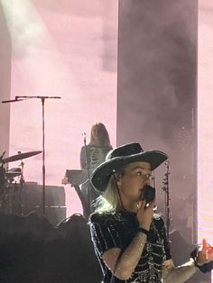 a woman in a cowboy hat singing into a microphone while standing next to another woman on stage