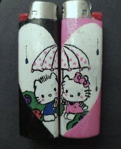 two hello kitty lighters sitting next to each other on top of a black surface