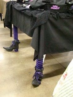 a table topped with lots of black clothing and purple socks on it's legs