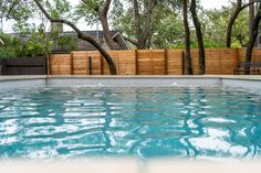 an empty swimming pool surrounded by trees and fence