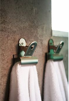 two towels are hanging on the wall next to each other with scissors and hooks in them