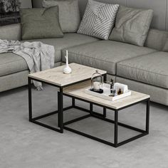 two tables sitting on top of each other in front of a gray couch and ottoman