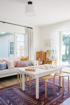 a living room filled with furniture and lots of windows next to a white couch sitting on top of a rug