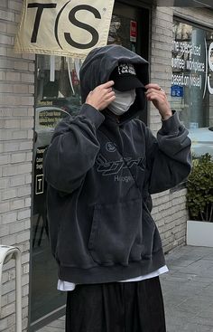 a person wearing a hoodie and covering his face with a mask on the street