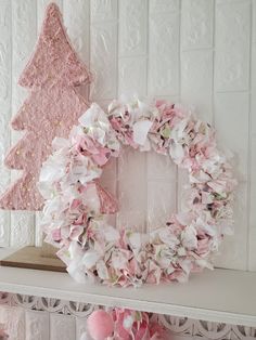 a pink christmas wreath sitting on top of a mantle