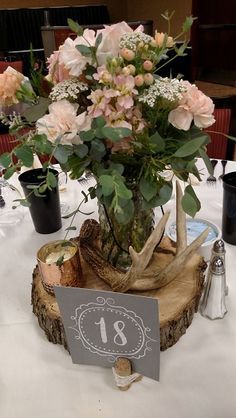 a centerpiece with flowers in a vase on top of a tree stump at a wedding reception