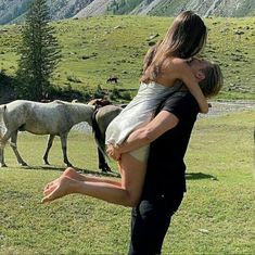 a man carrying a woman on his back in front of horses