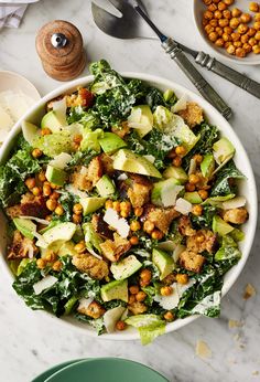 a white bowl filled with lettuce, chickpeas and other food items