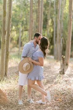 a man and woman are hugging in the woods with hats on their heads as they stand next to each other