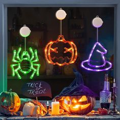 lighted pumpkins and witches in front of a window with trick or treat written on it