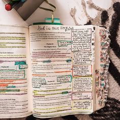 an open book with writing on it sitting on top of a rug next to a plant