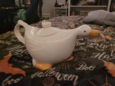 a teapot shaped like a duck sitting on top of a bed