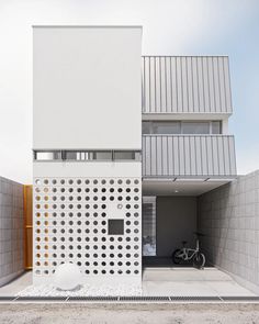 the house is made out of white bricks and has a bike parked in front of it