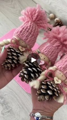 someone is holding some pine cones in their hands and wearing pink knitted mittens