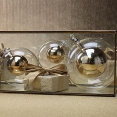 three glass ornaments in a box with a bow