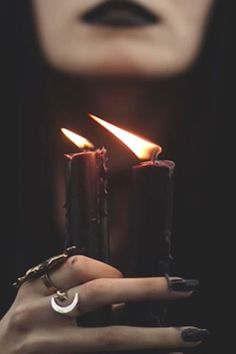 a woman holding two candles in her hands with one candle lit up and the other on her finger