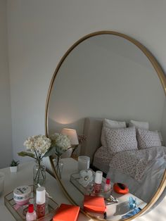 a round mirror sitting on top of a table next to a vase filled with flowers