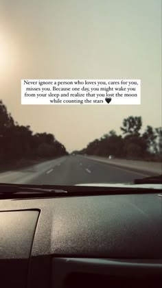 a car driving down a road with the sun shining in the background and text on the windshield