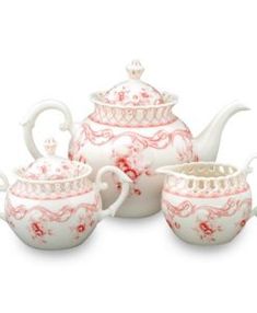 three teapots and two cups on a white surface