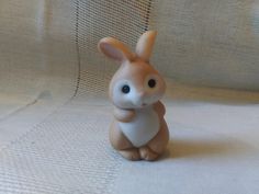 a small toy rabbit sitting on top of a white cloth