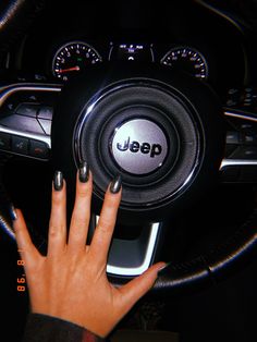 a woman's hand on the steering wheel of a car