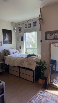 a bed room with a neatly made bed next to a window and a plant on the floor