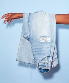 a person holding up a pair of jeans with their hands on the back of them