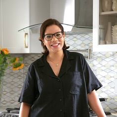 a woman standing in the kitchen wearing glasses