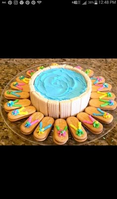 a cake with blue frosting surrounded by cookies and decorations on a glass platter