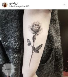 a woman's arm with a single rose tattoo on the left side of her arm